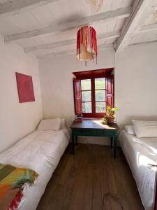 two beds in a room with a table and a window at Cal Mengo in La Vega