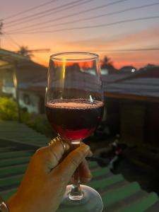 a person holding a glass of wine at sunset at Ruen Rinna home stays in Surin