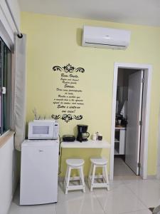 a kitchen with a microwave and a counter with stools at Pousada da Drica in Saquarema