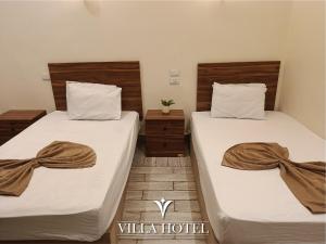 two beds in a hotel room with towels on them at Villa Downtown Hotel in Cairo