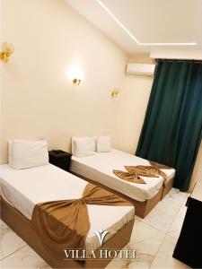 two beds in a room with green curtains at Villa Downtown Hotel in Cairo