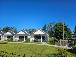 a large white house with a yard at Domki BAMBINO in Sarbinowo