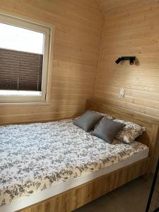 a bed in a log cabin with a window at Domki BAMBINO in Sarbinowo
