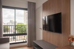 a living room with a television and a large window at Essential comfort - Vila Mariana in São Paulo