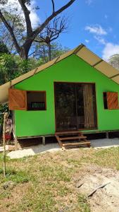 a green house with a large window in front of it at Casa AllíS in Cóbano