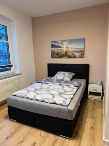a bed in a bedroom with a painting on the wall at Pension zum Kanal in Burg bei Magdeburg