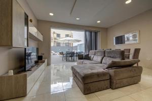 a living room with a couch and a television at Central Oasis - Private Pool & Lounge Area in Santa Vennera