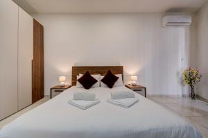 a bedroom with a large white bed with two pillows at Central Oasis - Private Pool & Lounge Area in Santa Vennera +41 photos