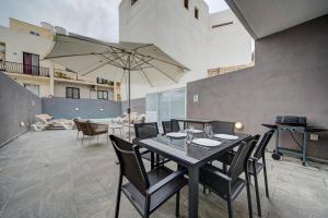 a dining room with a table with chairs and an umbrella at Central Oasis - Private Pool & Lounge Area in Santa Vennera