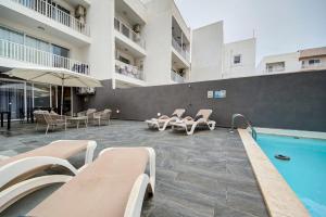 a hotel with a pool and chairs and a building at Central Oasis - Private Pool & Lounge Area in Santa Vennera