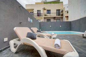 a group of chaise lounges on a patio with a pool at Central Oasis - Private Pool & Lounge Area in Santa Vennera