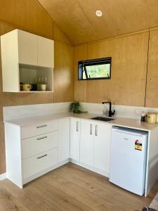a kitchen with white cabinets and a white refrigerator at Hikuai Hideaway in Hikuai