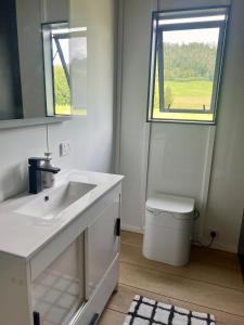 a white bathroom with a sink and a window at Hikuai Hideaway in Hikuai