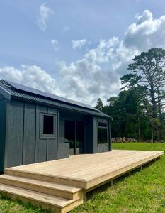a smallshed with a wooden deck in a field at Hikuai Hideaway in Hikuai +5 photos