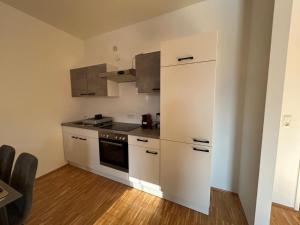 a kitchen with white cabinets and a refrigerator at Faraway Homes Studio Krieglach #7 in Sommer +5 photos