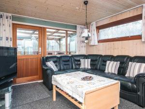a living room with a black leather couch and a coffee table at 4 person holiday home in Juelsminde in Snaptun +23 photos