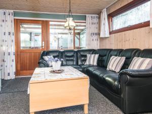 a black leather couch in a living room with a table at 4 person holiday home in Juelsminde in Snaptun
