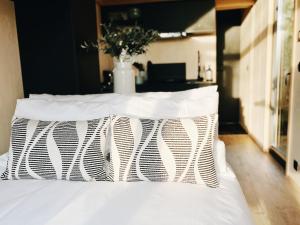 a white bed with white pillows on top of it at Tiny Cabin met airco en privé hottub in Rutten