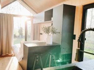 a small kitchen with a counter and stools in a room at Tiny Cabin met airco en privé hottub in Rutten