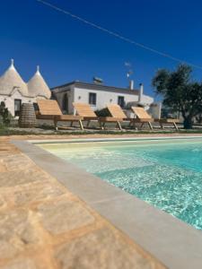 a swimming pool with benches next to a house at Trulli Enjoy in Noci