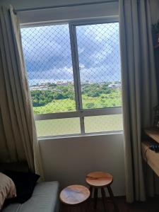 a room with a large window with two stools at Apartamento da Lagoa in Londrina