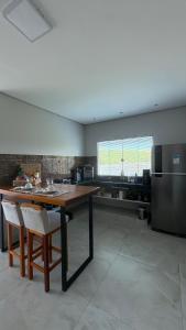 a large kitchen with a wooden table and a refrigerator at Cipó Lofts - 3 lofts incríveis na Serra do Cipó in Santana do Riacho