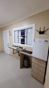 a kitchen with a counter and a refrigerator and a window at Cantinho do sossego in Capão da Canoa