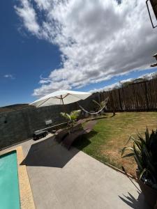 a patio with a white umbrella and chairs and a pool at Cipó Lofts - 3 lofts incríveis na Serra do Cipó in Santana do Riacho