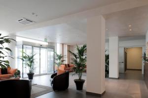 a lobby with chairs and plants in a building at Blu Arena Hotel in Montecchio