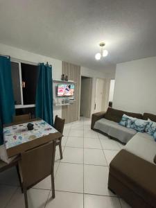 a living room with a couch and a table at Apt 2 quartos- Leia sobre a propriedade in Itamaracá
