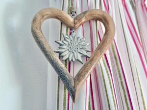 a wooden heart hanging on a wall with a snowflake at Sonnenhof Seeg 04 in Seeg