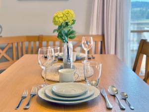 a wooden table with plates and glasses and a vase with yellow flowers at Sonnenhof Seeg 04 in Seeg