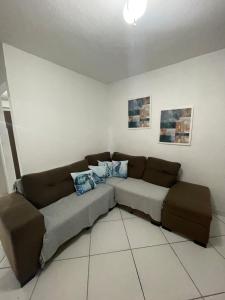 a living room with a brown couch and blue pillows at Apt 2 quartos- Leia sobre a propriedade in Itamaracá
