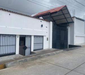 a white building with two doors and a gate at Condor Palace in Huayllay