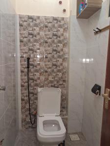 a bathroom with a toilet and a stone wall at Town Stays in Voi