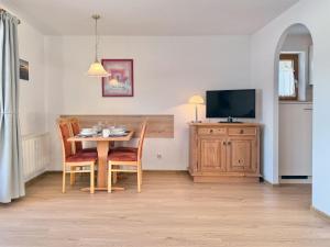 a dining room with a table and chairs and a tv at Sonnenhof Seeg 07 in Seeg