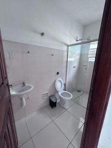 a white bathroom with a toilet and a sink at Casa espaçosa 100m da praia in Ubatuba +8 photos