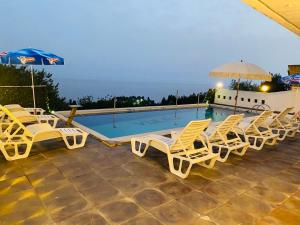 a group of lounge chairs and a swimming pool at Rozana Rooms in Ulcinj