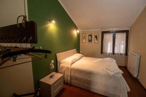 a bedroom with a white bed and a green wall at Casa sul fiume con giardino e terrazza in Pianello