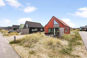 a red and black house in a field with houses at 940-Hvide-Sande-Langsand-169 in Hvide Sande
