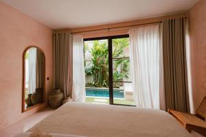 a bedroom with a bed and a large window at Alma Bingin Boutique Hotel in Uluwatu