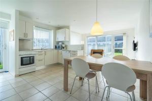 a kitchen with a wooden table and white chairs at 769-Hvide-Sande-Norregade-4-C in Hvide Sande