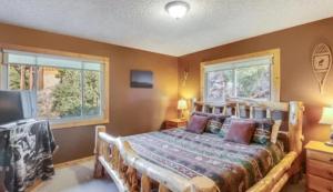 a bedroom with a wooden bed and two windows at Rocky Mountain Panorama Cabin in Estes Park +18 photos
