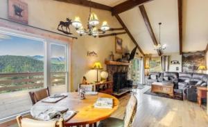 a living room with a table and a fireplace at Rocky Mountain Panorama Cabin in Estes Park