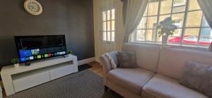 a living room with a couch and a flat screen tv at Windsor Castle amazing Cottage in Windsor