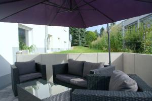 eine Terrasse mit einem Sonnenschirm, Stühlen und einem Tisch in der Unterkunft Hotel Beuss in Oberursel