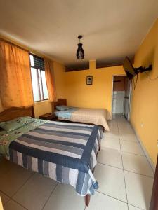 two beds in a room with yellow walls at Ugarte Street in Trujillo