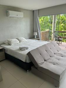 a large bed in a bedroom with a large window at Flat Villas do Pratagy: Tranquilidade e Natureza ao Norte de Maceió in Maceió
