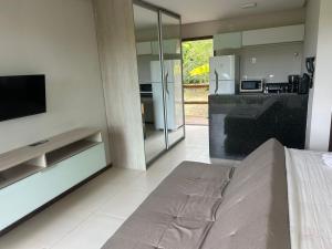 a kitchen with a bed and a television in a room at Flat Villas do Pratagy: Tranquilidade e Natureza ao Norte de Maceió in Maceió +7 photos