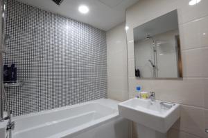 a bathroom with a white tub and a sink and a bath tubermott at Novahotel in Samgong